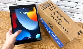 Someone holding an iPad next to an Amazon Prime Day box