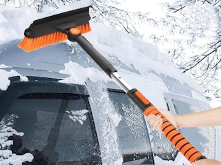 a person brushing snow off of a car with a snow brush