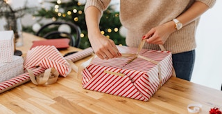 person wrapping a holiday gift with wrapping paper and ribbon