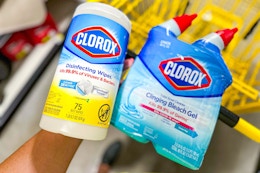 hand holding clorox products above yellow shopping cart