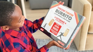 A young boy looking at the box of a Throw Throw Burrito game.