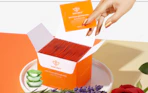 a hand pulling a pack of nail polish remover pads out of an orange box