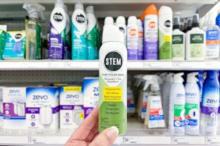 hand holding a stem mosquito and tick spray in front of a target shelf