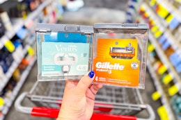person holding gillette and venus razor refill packs over a cart