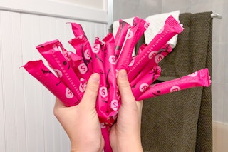 Woman holding tampons fanned out in bathroom