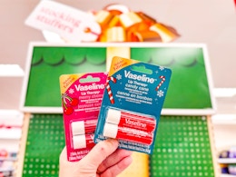 hand holding 2 vaseline lip therapy holiday sets in front of target signage