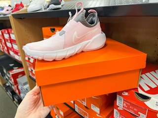 A pink nike shoe sitting on top a nike box.