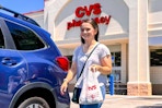 a woman walking out of CVS carrying a bag