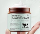 a hand holding a jar of cream