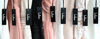 A close up on the tags of some dresses from Lulus hung on a rack