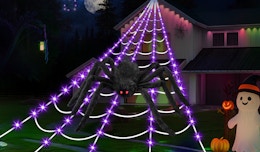 a giant faux spider in a web with purple lights