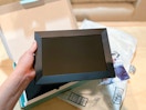a person holding a digital picture frame over packaging