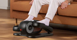 a person sitting on a couch using an under-desk elliptical