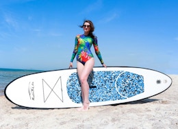 a person on a beach with a paddleboard 
