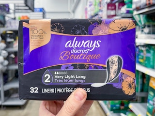 An Always Discreet Boutique package held out by hand in front of a store aisle.