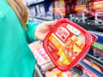woman holding a tub of hillshire farm deli meat in walmart aisle