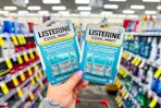 person holding 2 packages of listerine pocketpacks in an aisle