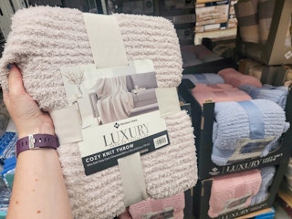 a hand holding a luxury knit throw blanket