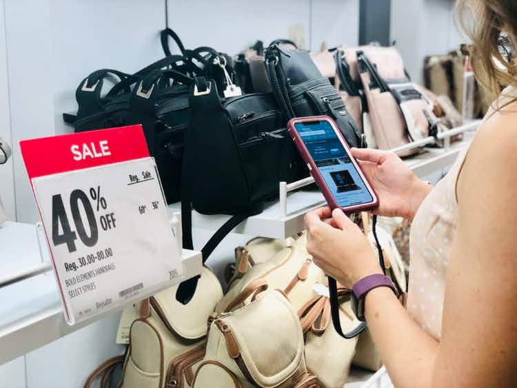 Shopper looking up prices of bags at JCPenney on phone
