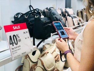 Shopper looking up prices of bags at JCPenney on phone
