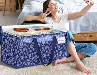 a person sitting next to a blue moving bag in a room