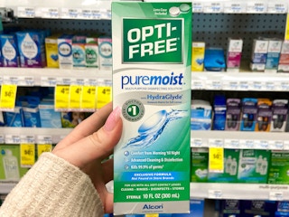 a person holding up opti free in a cvs