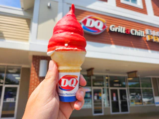 Someone holding up a cherry dipped ice cream cone at Dairy Queen