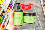 person holding mielle shampoo and hair mask bottles over a cart