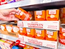 hand holding a can of libbys pumpkin puree on walmart shelf