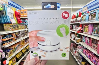 person holding a portable mini desktop vacuum in an aisle