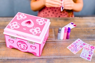 Lifestyle image of the Melissa & Doug Jewelry Craft kit being used by a child in the background