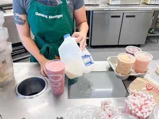 employee holding milk next to smoothie