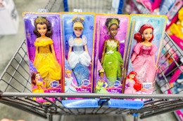 Belle, Cinderella, Tiana, and Ariel Disney Princess dolls in a Walmart cart
