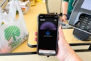 A person's hand holding a cellphone with apple pay on screen at the dollar tree register about to pay.