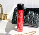 a red can of hairspray on a sink next to a purse