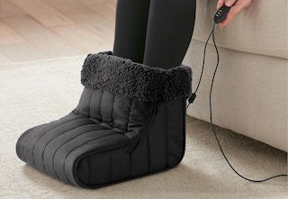 A person wearing a Shavel Heated Foot warmer in a living room. 
