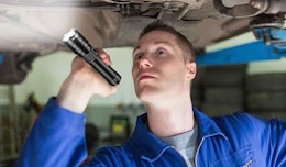 a person using a flashlight to look under a car