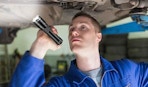 a person using a flashlight to look under a car
