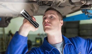 a person using a flashlight to look under a car