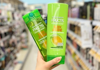 hand holding two bottles of Garnier Fructis shampoo and conditioner