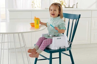 A young girl on a booster seat at a table