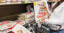 a person putting large bags of dog food into petco cart