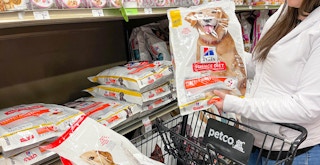 a person putting large bags of dog food into petco cart