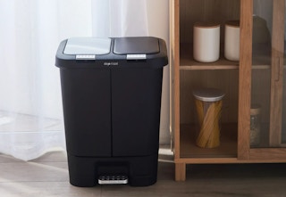 dual trash recycling bin sitting next to pantry in front of window