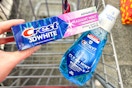 person holding crest toothpaste over crest mouthwash in a cart