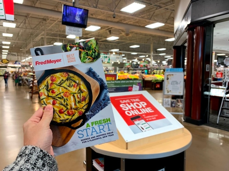 A person holding Fred Meyer best customer bonus coupon mailer.