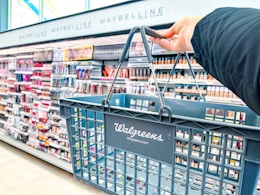 hand holding walgreens shopping basket in front of maybelline display