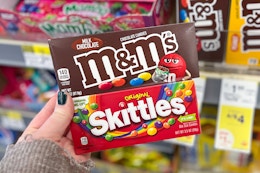 hand holding m&ms and skittles theatre box candy