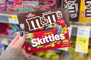 hand holding m&ms and skittles theatre box candy