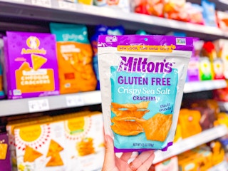 hand holding a bag of miltons crackers in walmart aisle